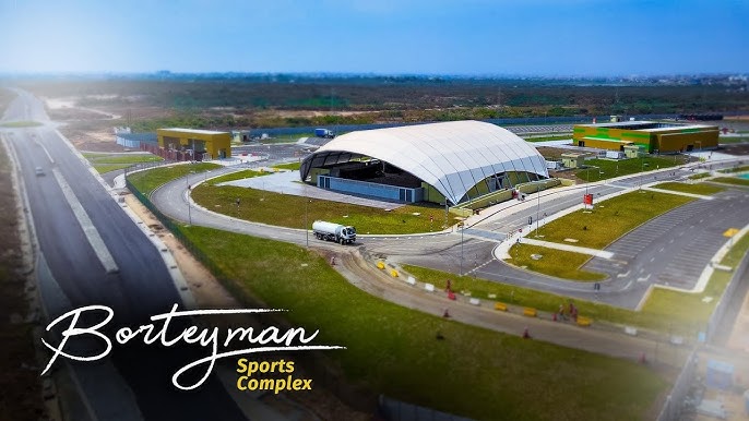 Aerial view of Borteyman Sports Complex showcasing its modern facilities and architectural design, surrounded by landscaped areas and roads, highlighting its role as a premier sports venue in Ghana.