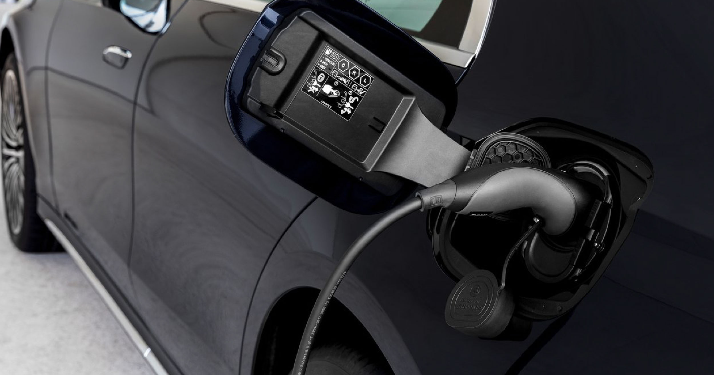 Close-up of the charging port of the 2024 Mercedes-Benz E-Class plug-in hybrid, showcasing the charging cable connected to the vehicle for eco-friendly electric power.